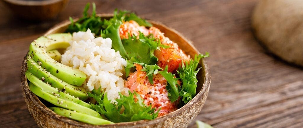 Hawaiian poke coconut bowl with grilled salmon fish, rice and avocado