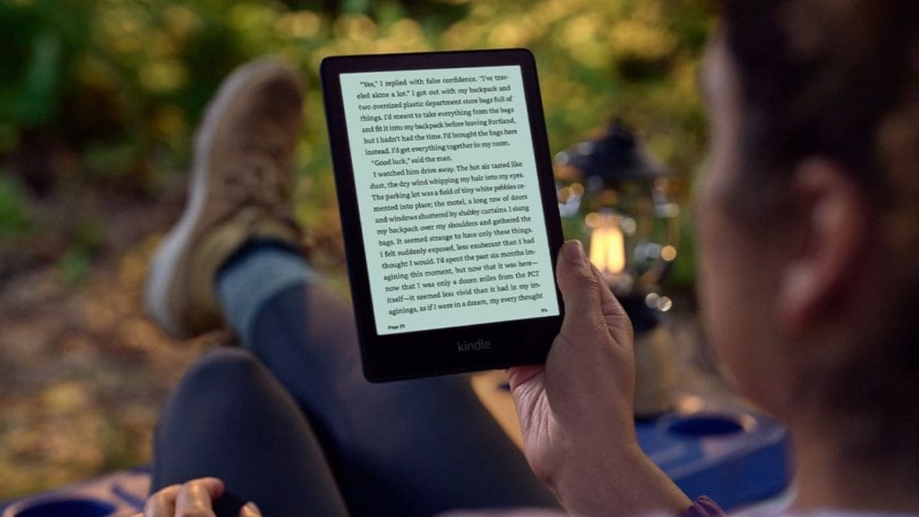 Woman using an Amazon Kindle eBook reader in a camp