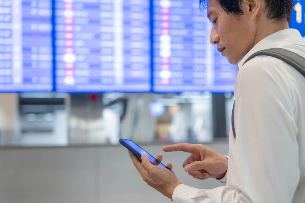 Man using mobile phone to book error fare plane ticket